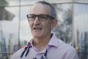 A man in dark glasses and a stethoscope looks at the camera.