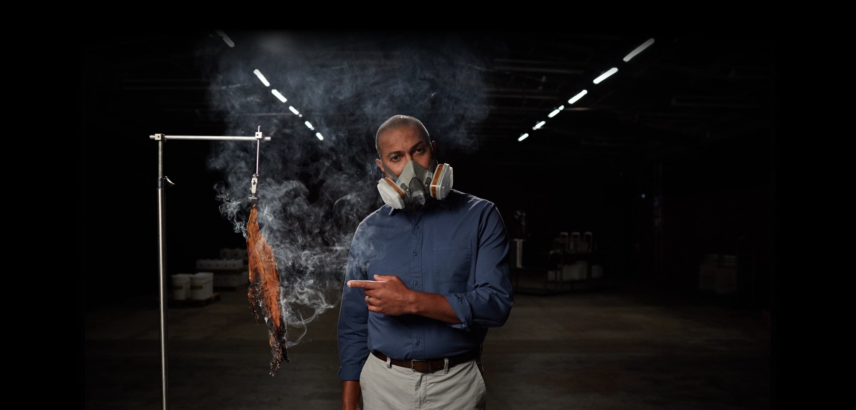 A man in a gas mask burns dried tobacco