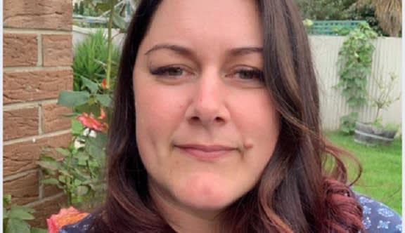 A woman in a garden smiles at the camera