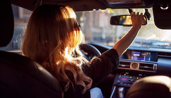 A woman checks her car's rearview mirror