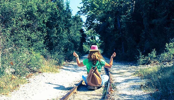 A person sitting down on train tracks meditating