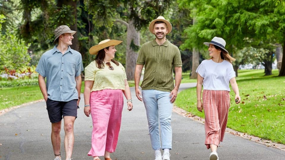 A group of four friends walking along a path in a park