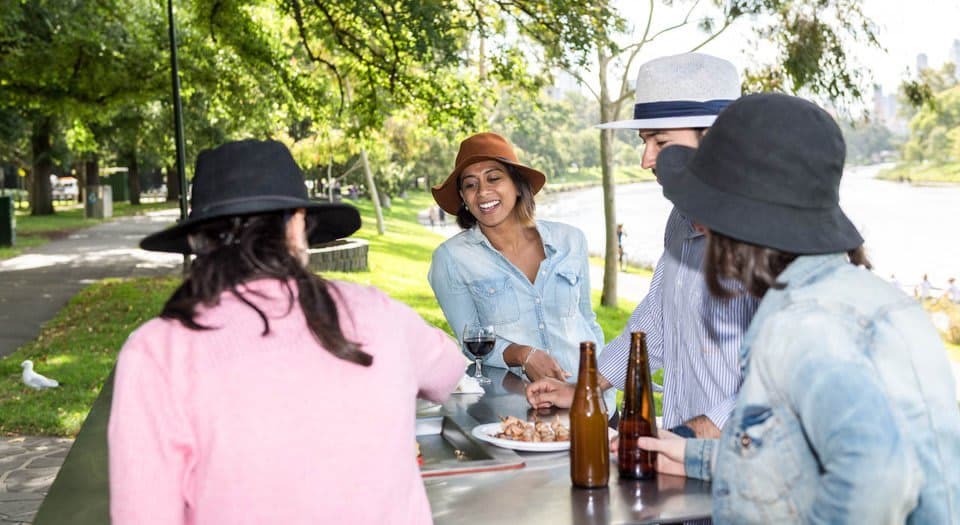 Four friends having a barbecue in a park