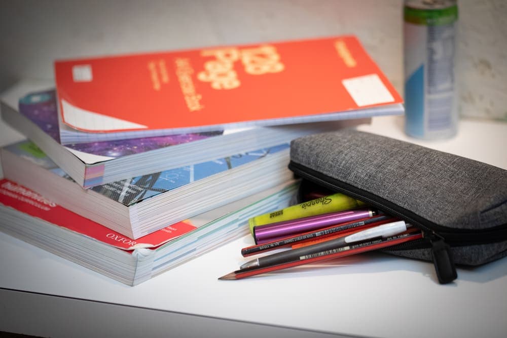 A pencil case that has a vape next to the pencils and pens