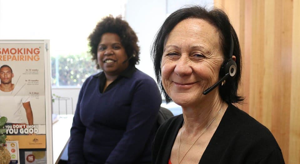Two Quitline counsellors smile