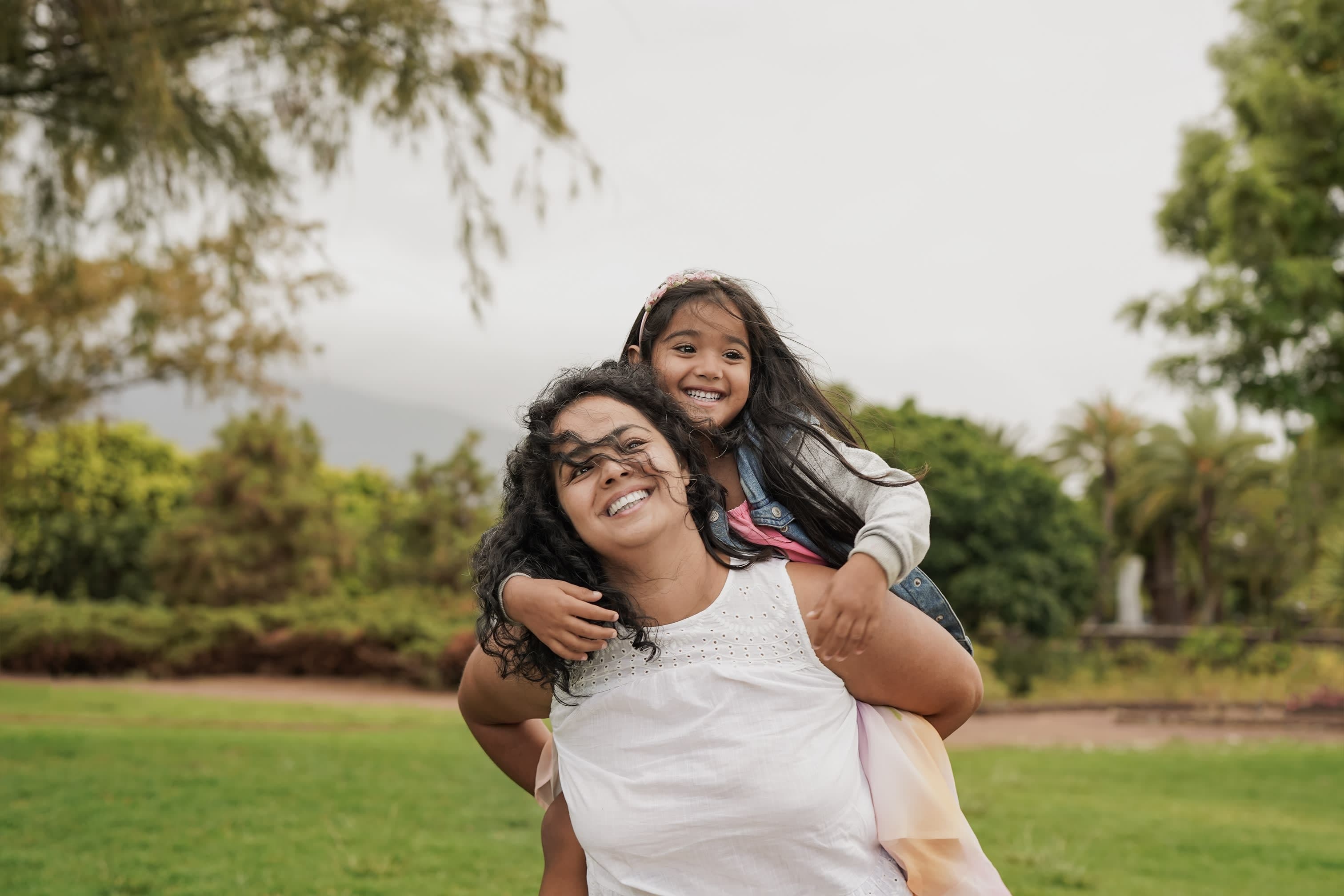 A mother carries her child on her back in the park
