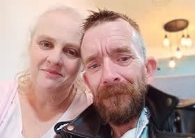 A bearded man with a supporter looks at the camera