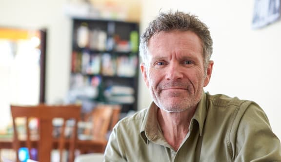 An older man looks at the camera